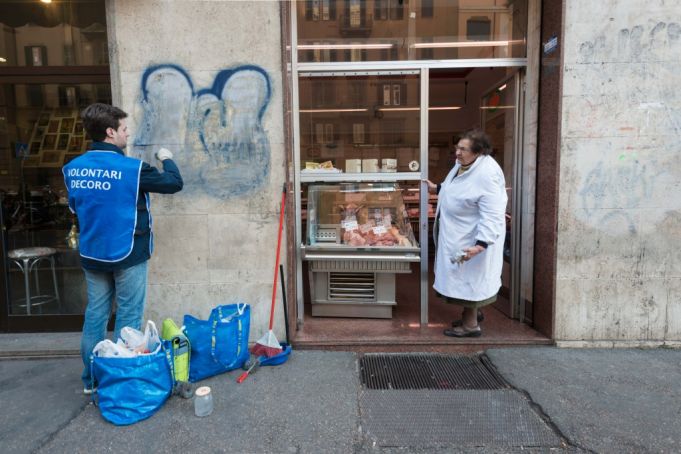 A Retake Roma volunteer removes graffiti from a shopfront on Viale Eritrea in the Nomentana district. Photo Matteo Natalucci.