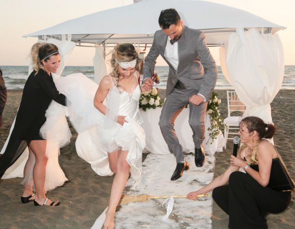 Alessia and Alessandro jumping the broom with celebrant Sarah Morgan (right) from Passaggi.